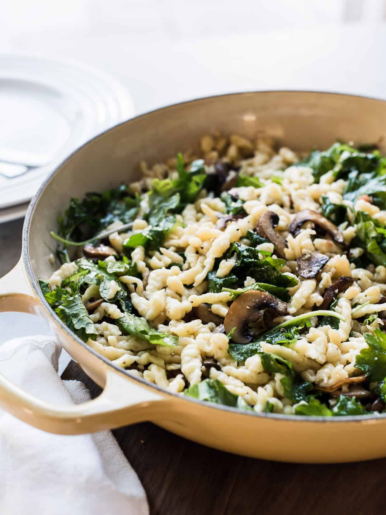 Deep sauté pan filled with homemade Spaetzle with Garlic Butter Mushrooms and Baby Kale.