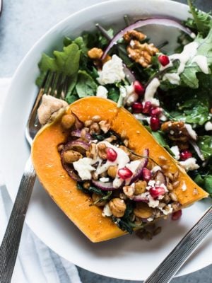 Quartered Stuffed Butternut Squash prepared with chickpeas, farro, kale, walnuts, and more.