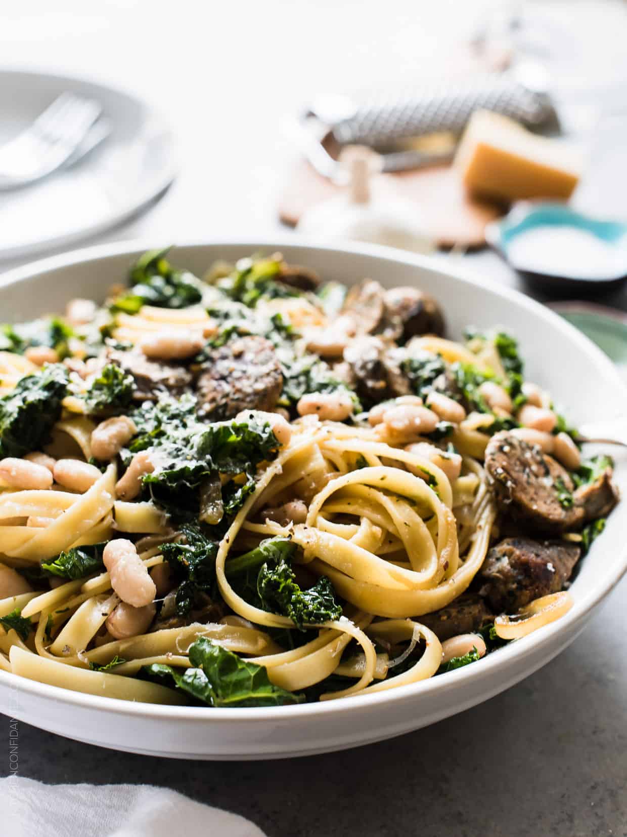 Fettuccine with Chicken Sausage, Kale and Cannellini Beans piled high in a white bowl.