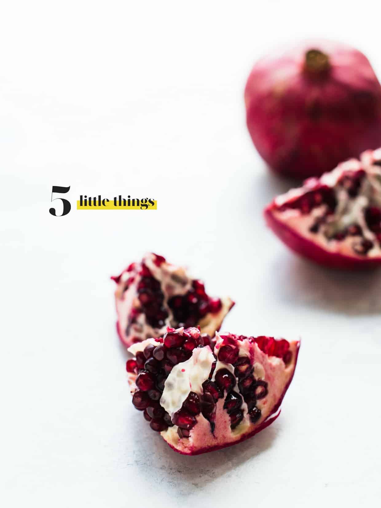 Pomegranate split into segments on a white surface.