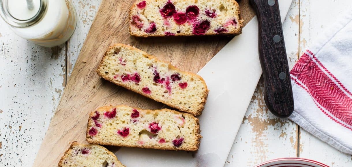 Slices of Cranberry Tea Cake on a marble and wood cutting board.