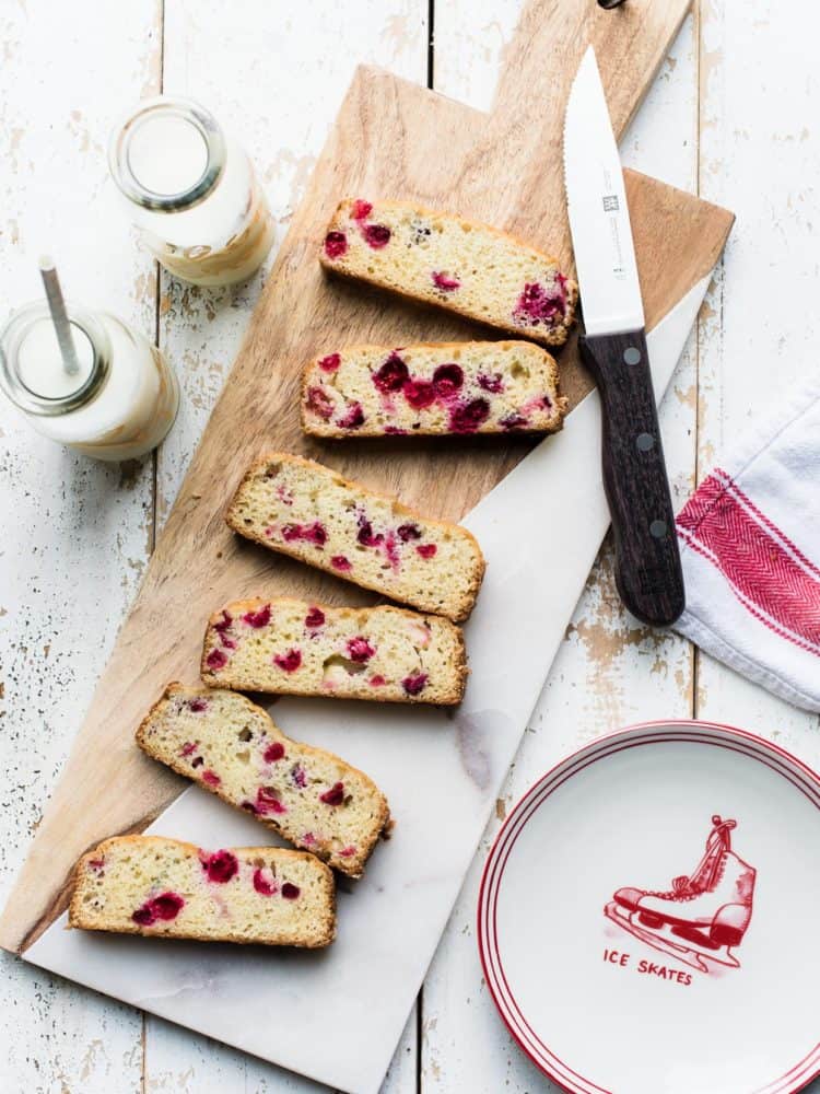 Slices of Cranberry Tea Cake on a marble and wood cutting board.