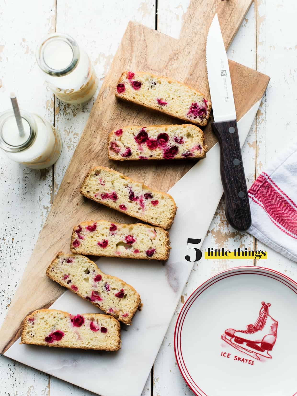 Slices of Cranberry Tea Cake on a marble and wood cutting board.