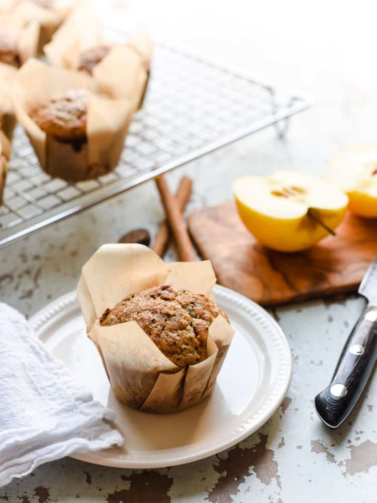 Applesauce Chia Muffin on a plate with apples in the background.