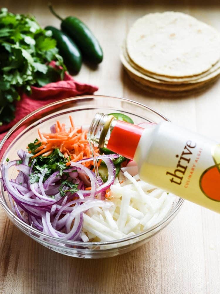 Using Thrive Culinary Algae Oil to make Jicama Slaw in a glass bowl.