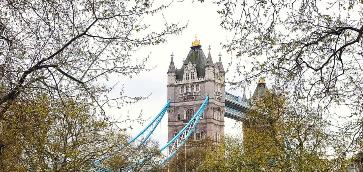 Tower Bridge in London with trees in the foreground and "A Taste of London: Family Travel Guide" text overlay.