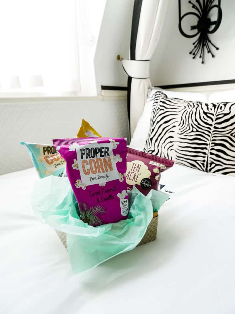 Bags of popcorn snacks on a white hotel bed.