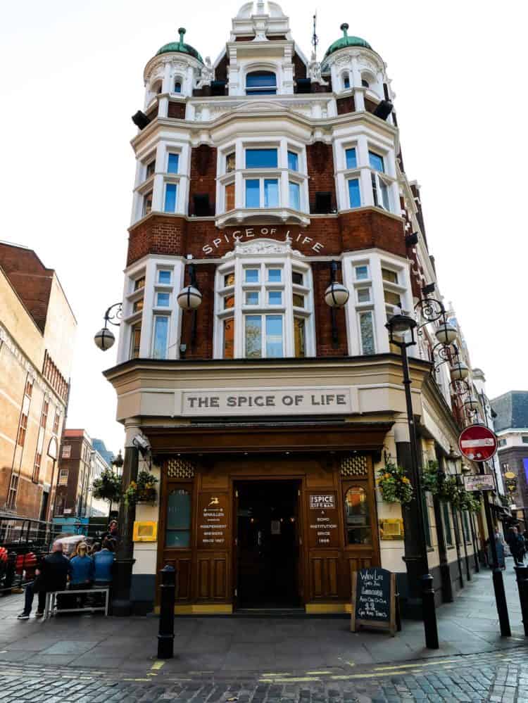 A tall, narrow brick building in London with lots of white windows. Sign says The Spice of Life.