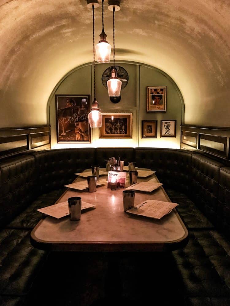 Dark and cozy restaurant booth under a small arch set for 6 people.