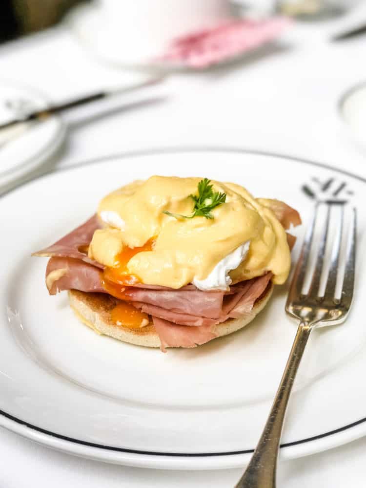 Eggs Benedict on a white plate with a fork.