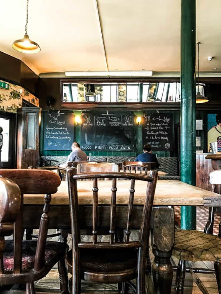 Bright and rustic pub with mixed wooden chairs, chalkboards, and hunter green accents.