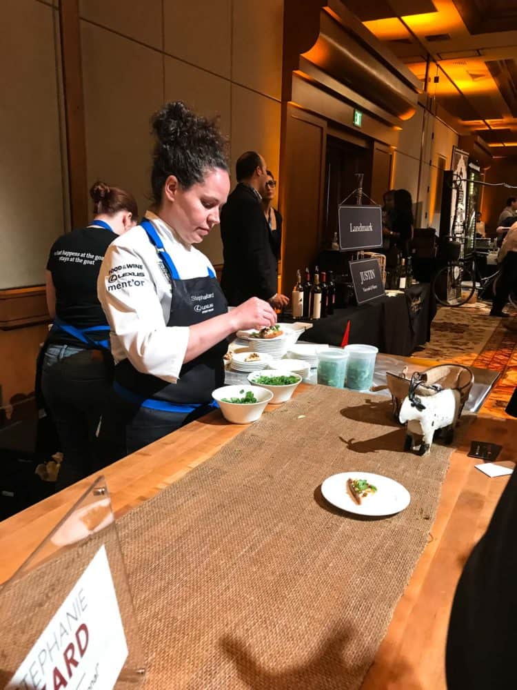 A woman in a chef coat and apron handling greens at the Pebble Beach Food & Wine.