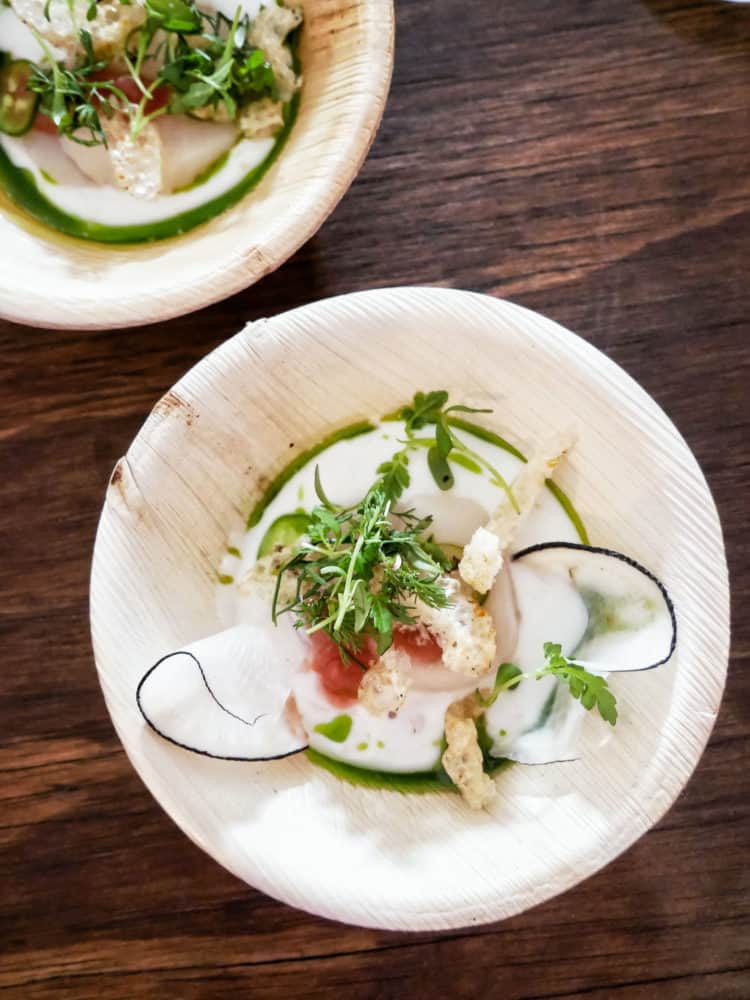Scallop Crudo in small wooden bowls with green garnishes at the Pebble Beach Food & Wine.