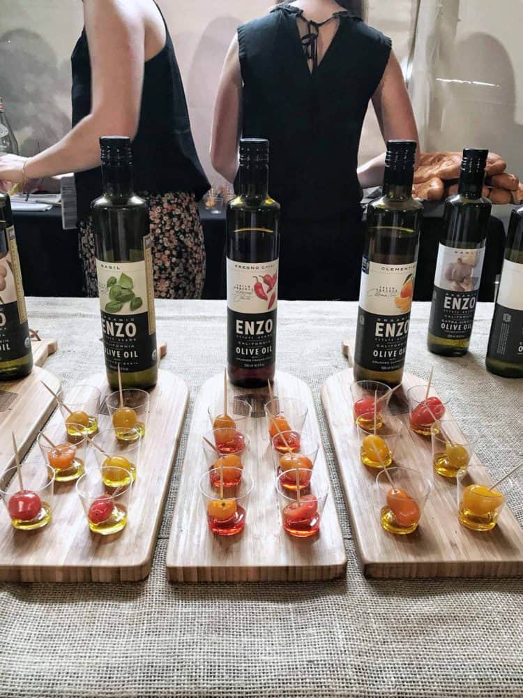 Olive oil bottles and tasting glasses lined up on wooden boards at the Pebble Beach Food & Wine.