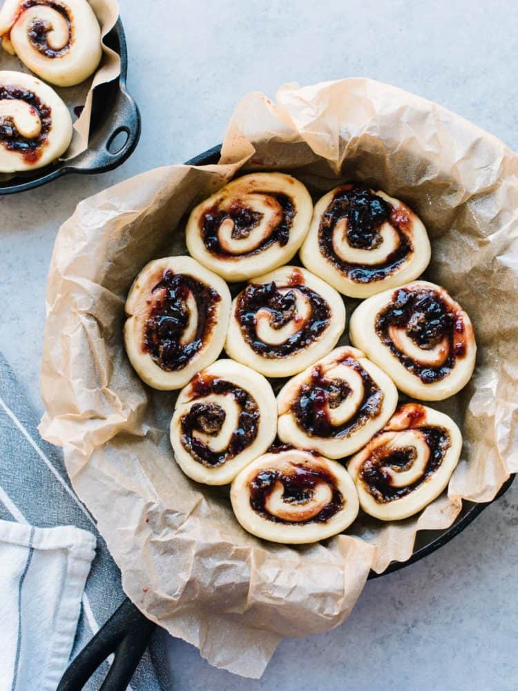 Cherry rolls waiting to be baken in a parchment lined cast iron pan.