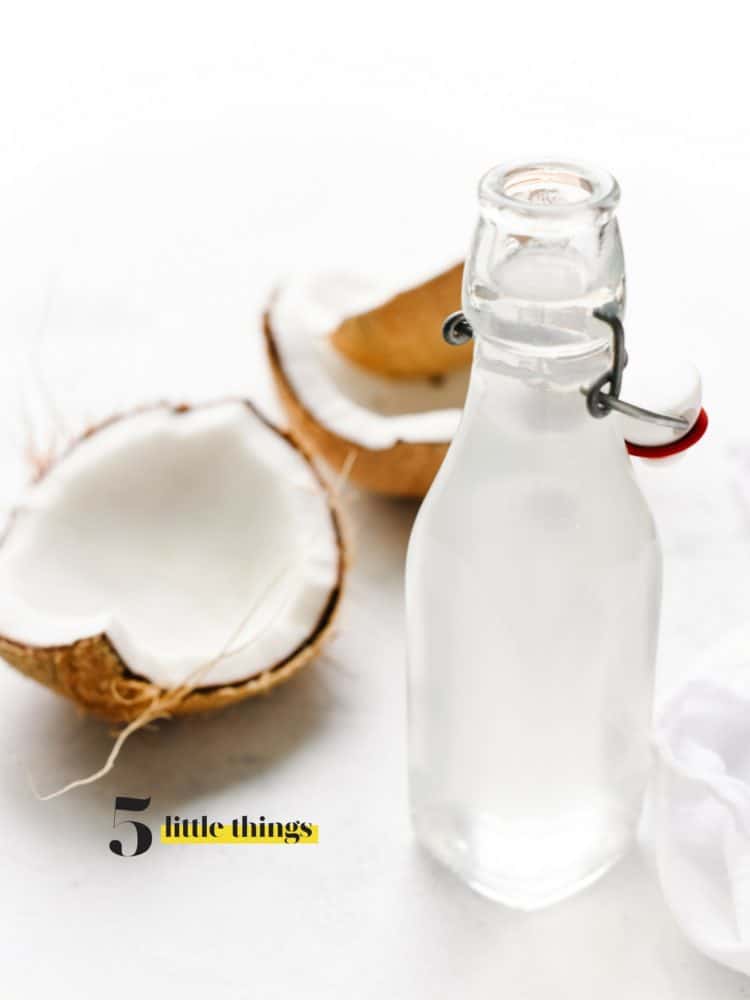 Glass bottle of homemade coconut water and large pieces of coconut