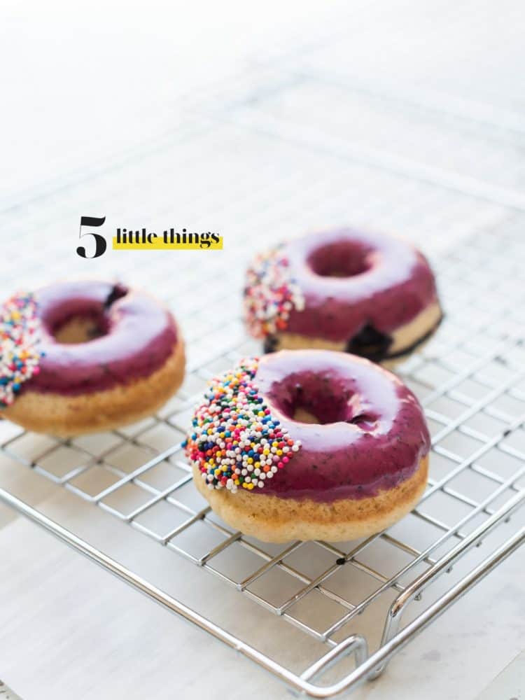 Blueberry glazed doughnuts with sprinkles on a cooling rack