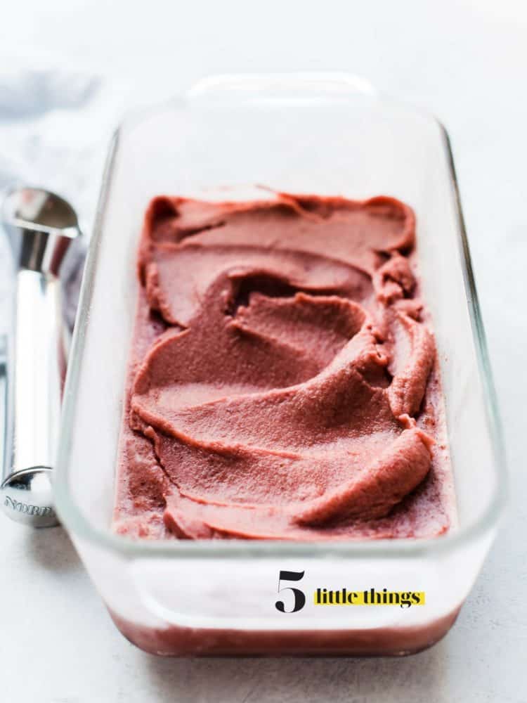 Cherry Basil Sorbet in a glass loaf pan with an ice cream scoop.