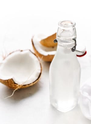 Glass bottle of homemade coconut water and large pieces of coconut