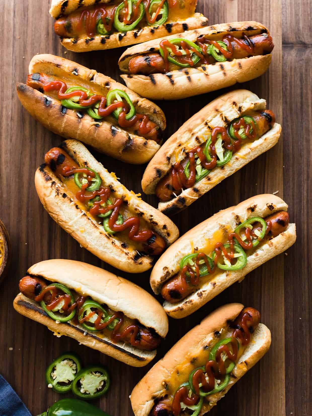 Sriracha Hot Dogs in buns with cheese and jalapeños.
