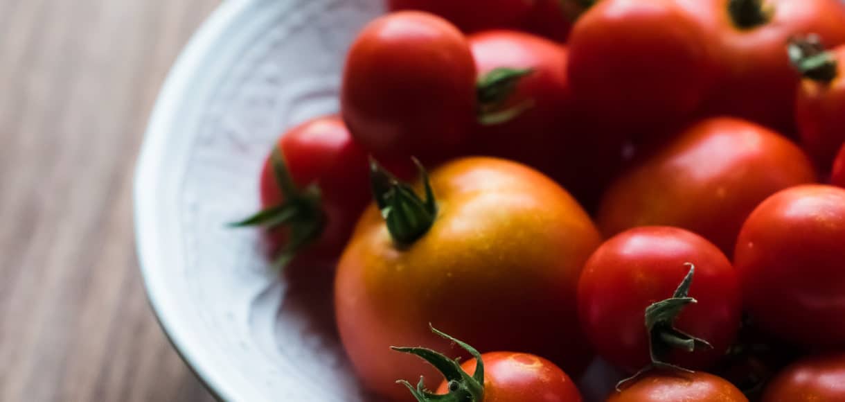 A white bowl filled with red tomatoes.