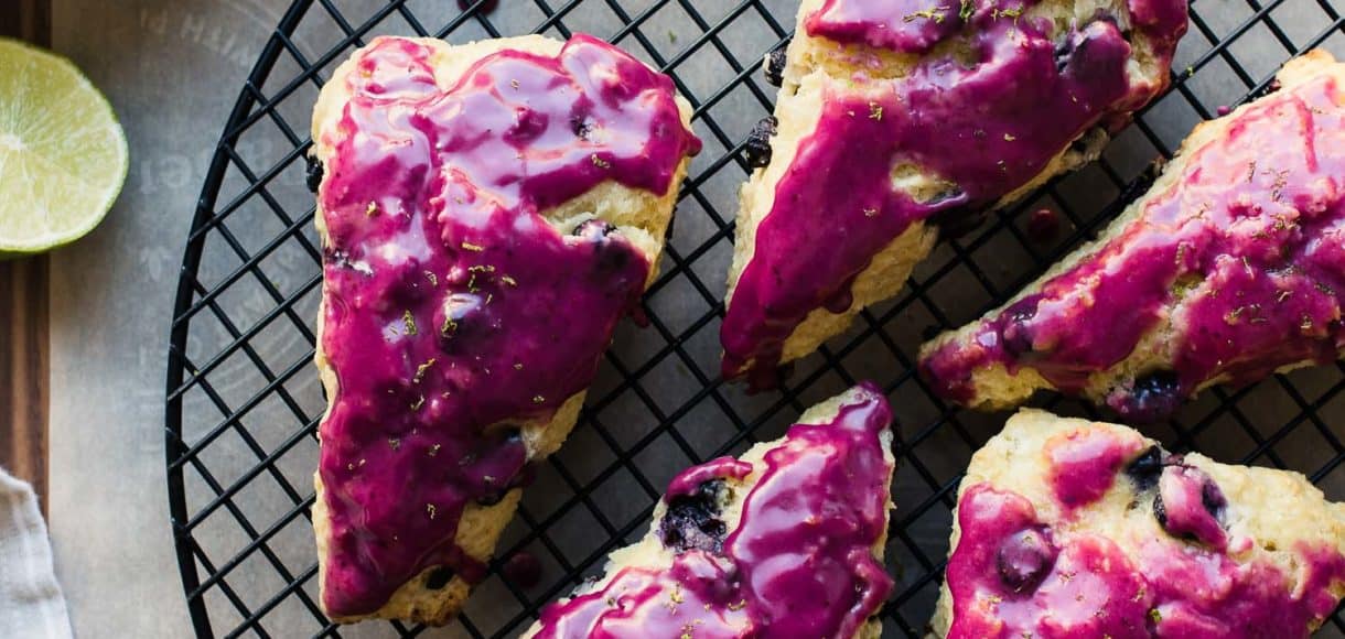Blueberry Goat Cheese Scones with fuchsia blueberry glaze on a cooling rack.