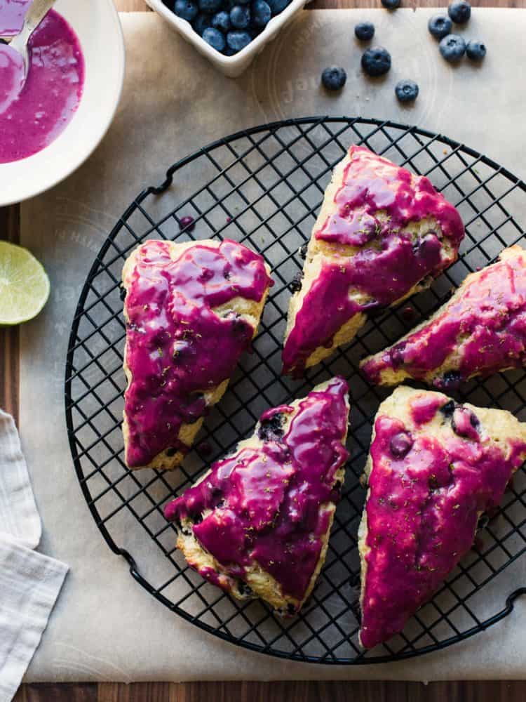 Blueberry Goat Cheese Scones with fuchsia blueberry glaze on a cooling rack.