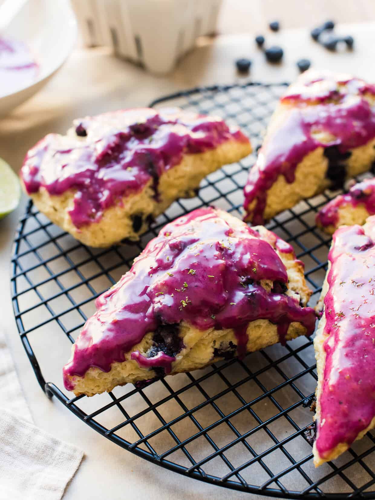 Blueberry Goat Cheese Scones with fuchsia blueberry glaze on a cooling rack.