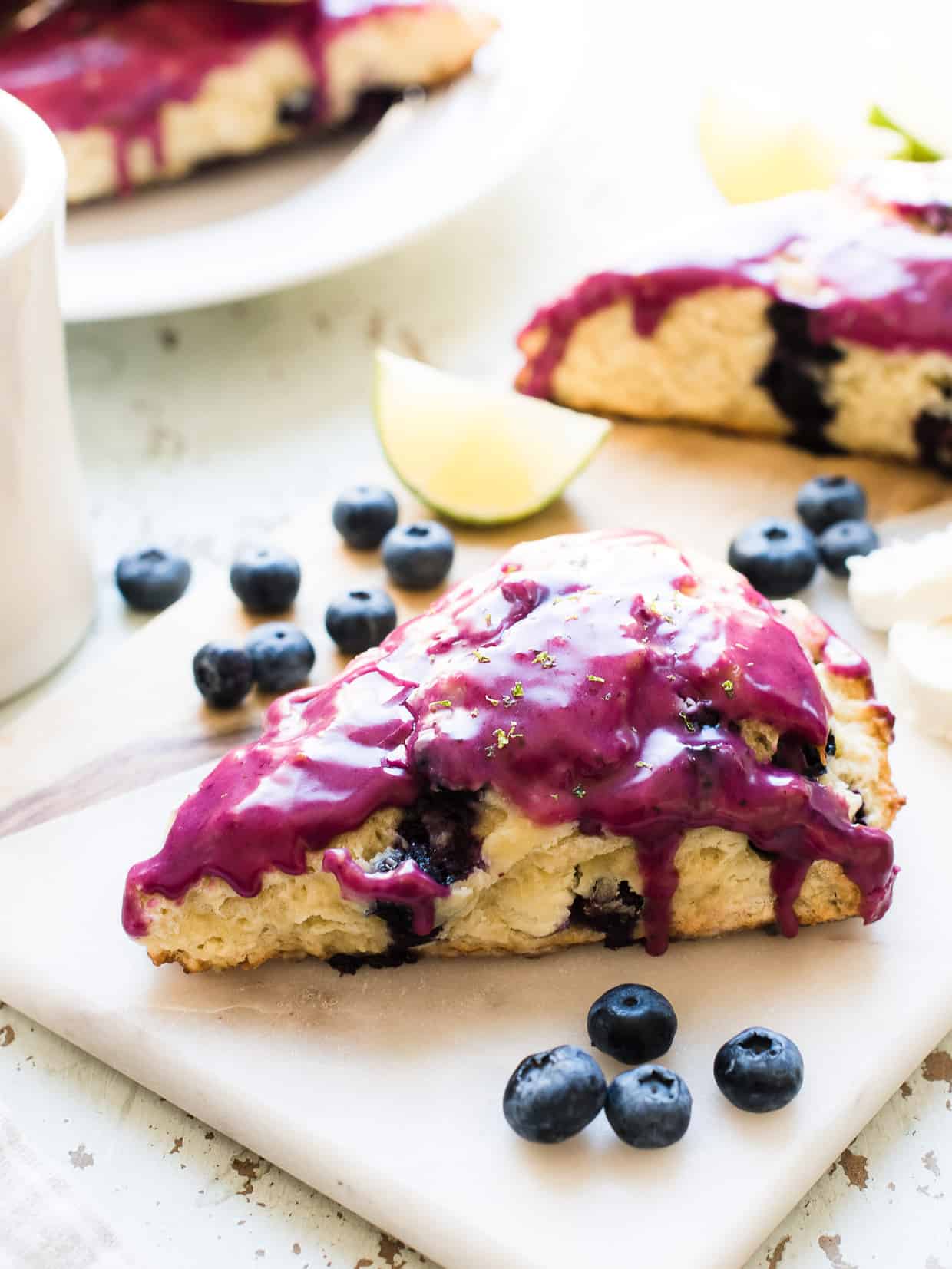 Blueberry goat cheese scones on a marble board with fresh blueberries.
