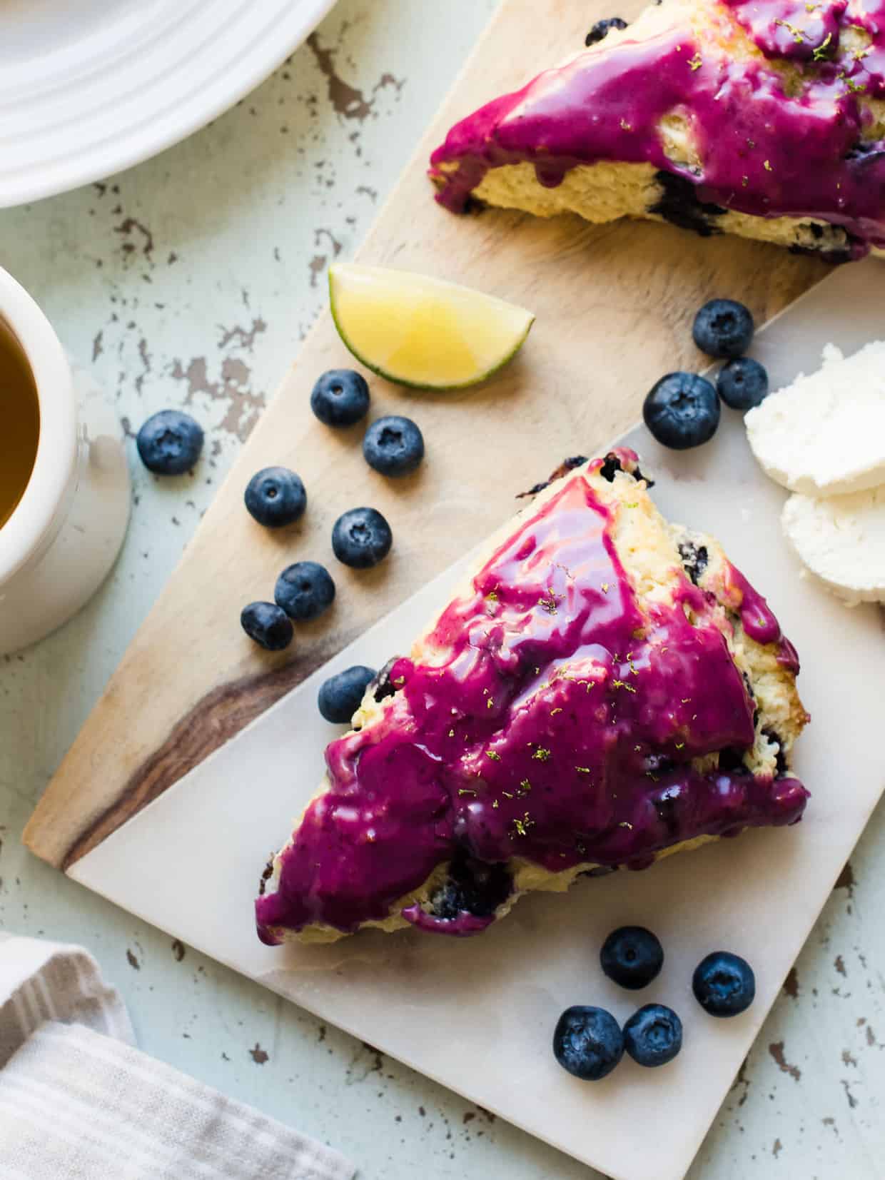 Blueberry goat cheese scones on a marble board with fresh blueberries.