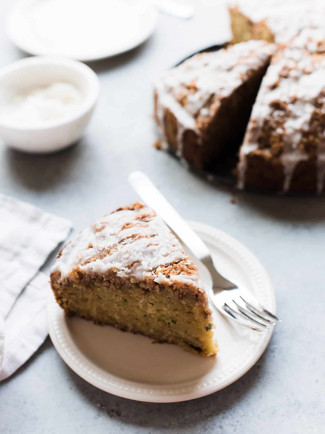 A slice of coconut zucchini coffee cake on a white plate.