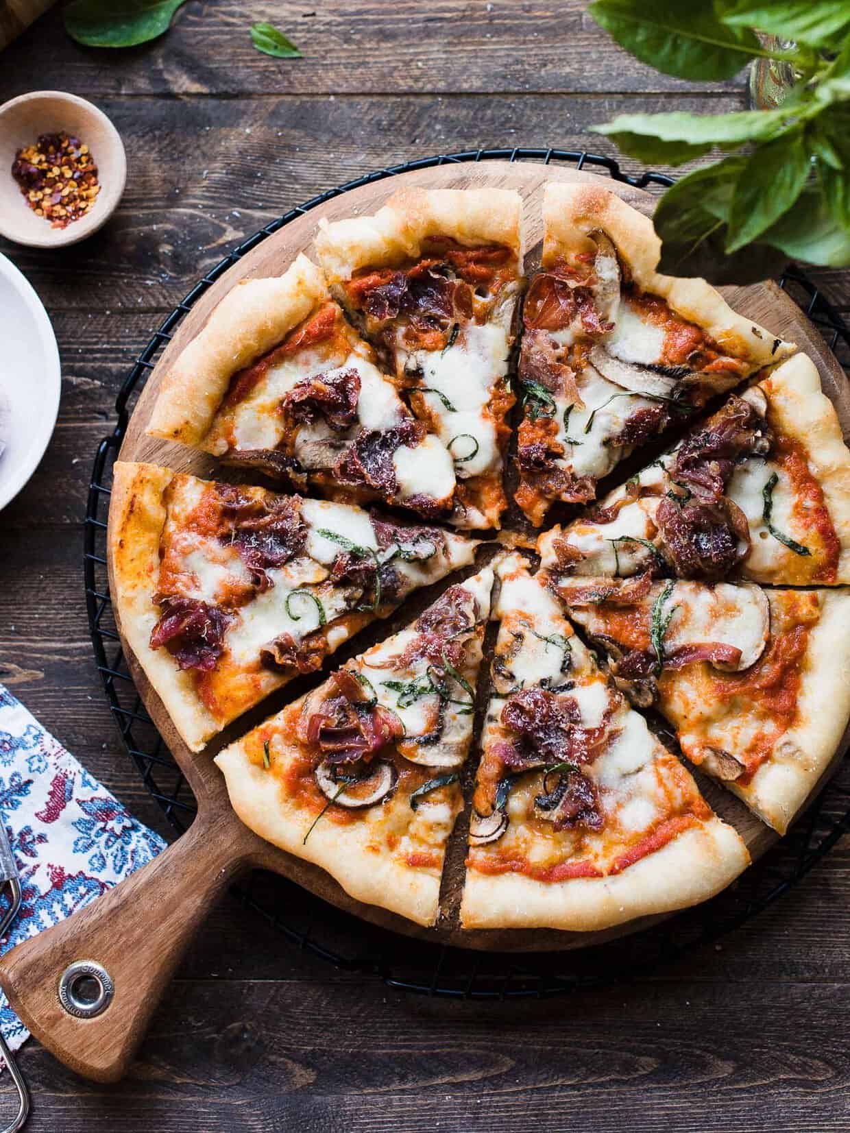 A freshly baked Dutch Oven Pizza sliced into eight pieces on a serving board.