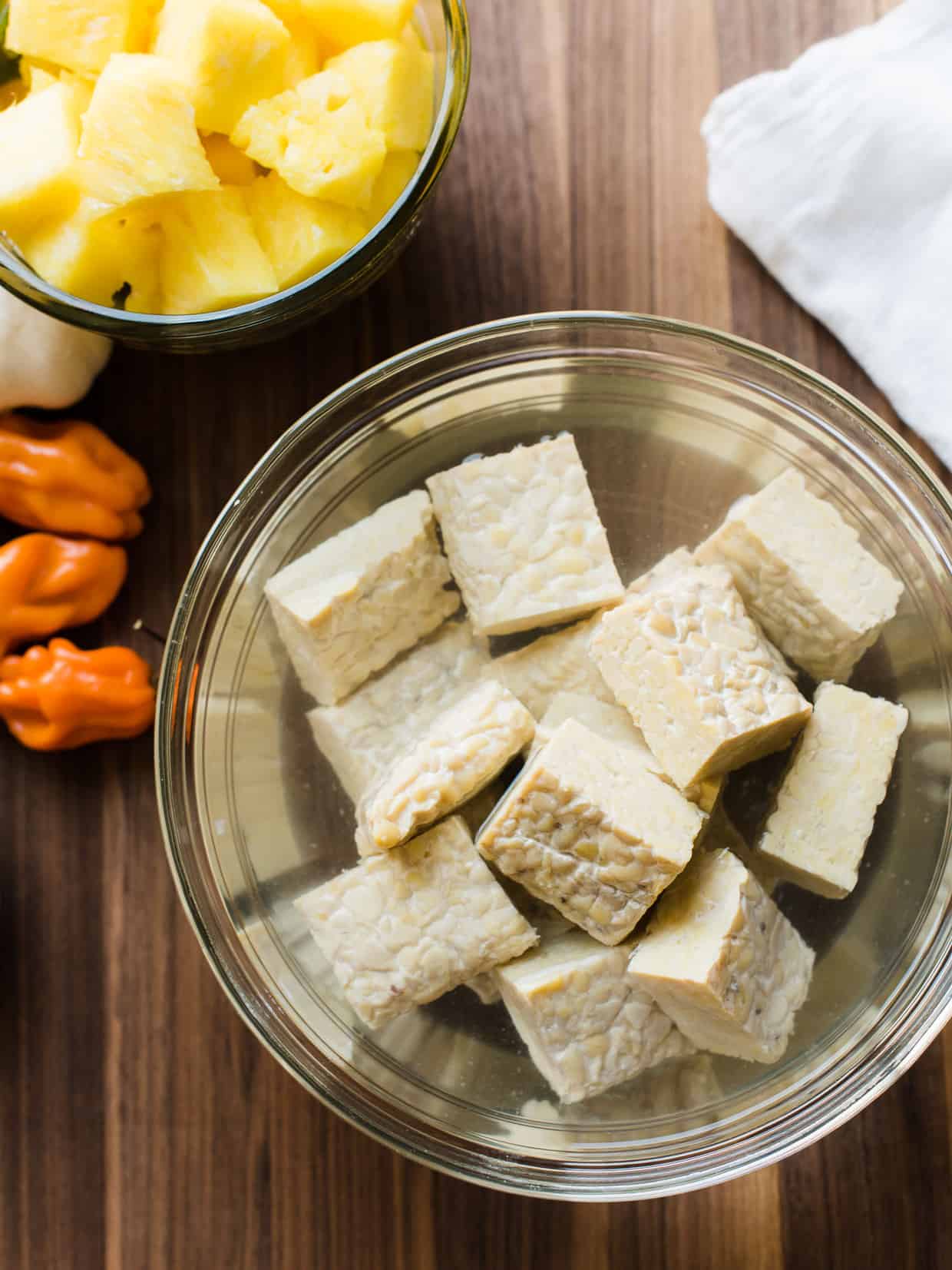 Cubes of tempeh soaking in a glass bowl to make Grilled Tempeh and Vegetable Skewers.