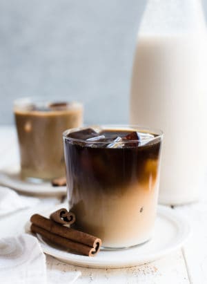 Horchata Cold Brew Latte in a glass with ice and cinnamon sticks.