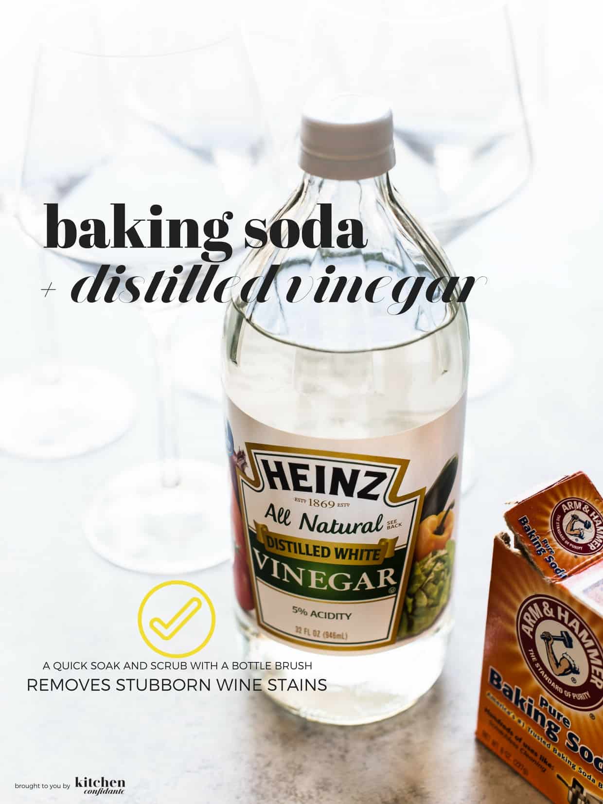 A bottle of distilled white vinegar and a box of baking soda with clean wine glasses.
