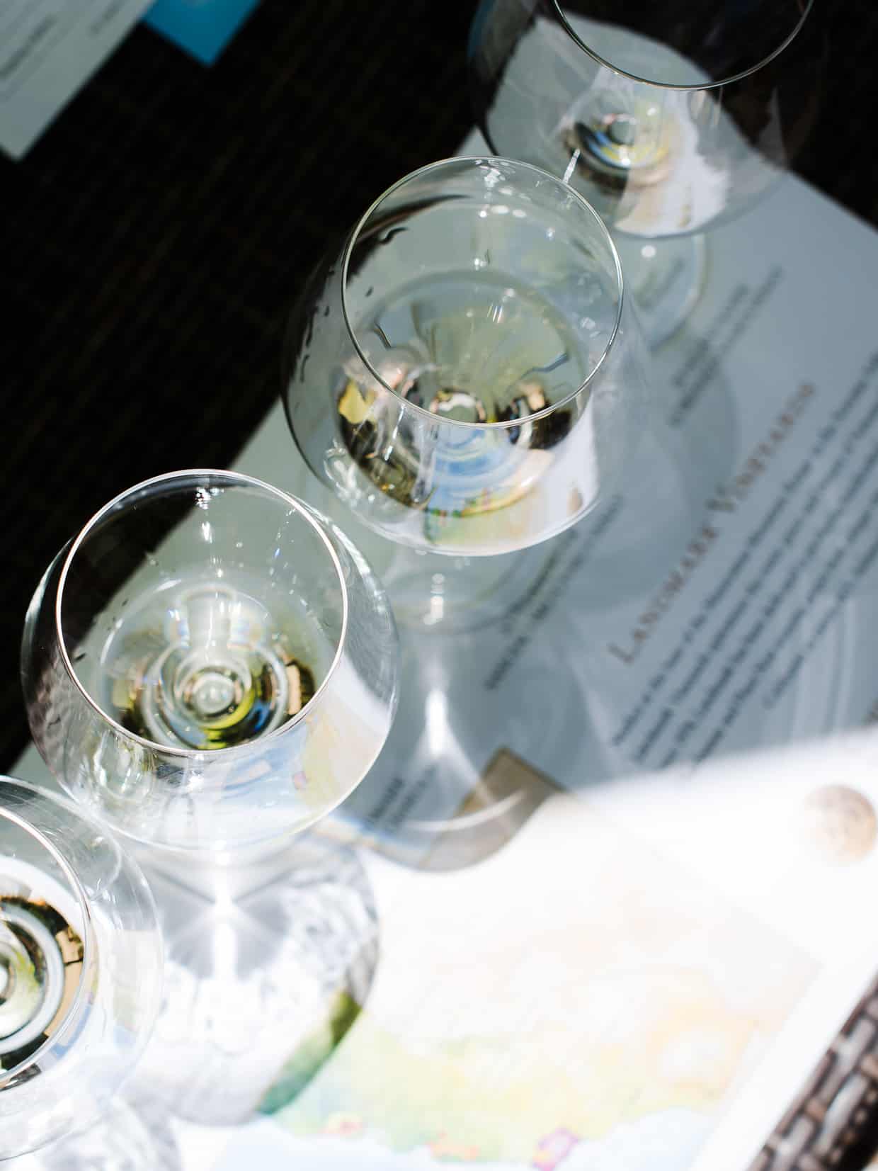 Top down view of 4 wine glasses with white wine at a wine tasting.