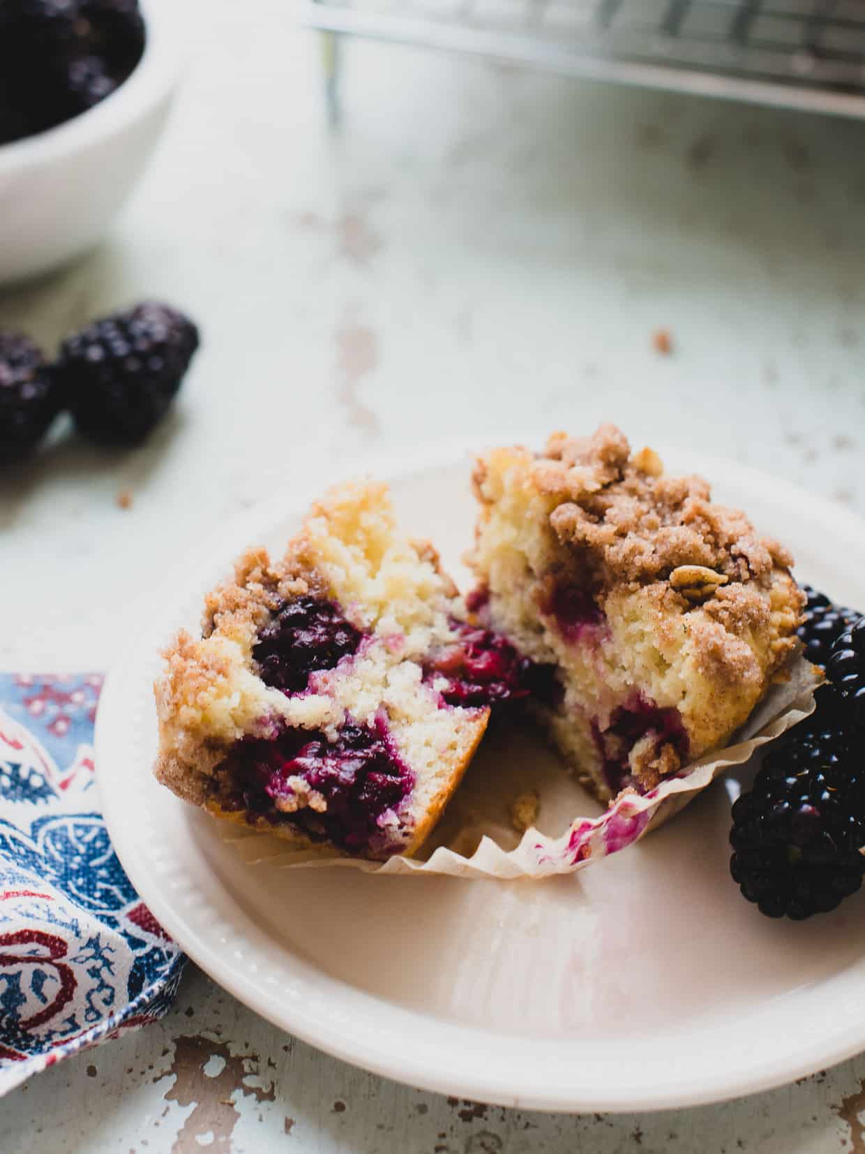 Freshly baked blackberry yogurt muffin cut in half on a white plate.