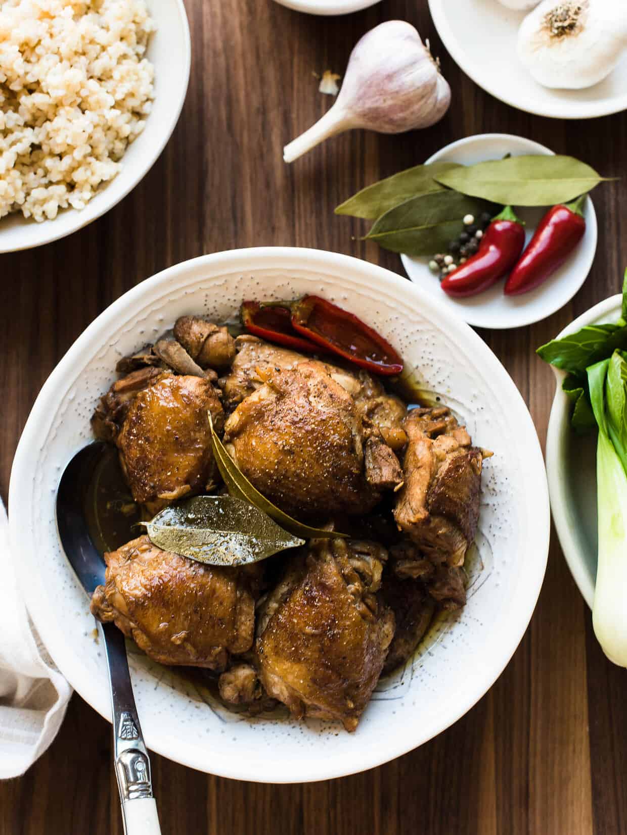 Dish of Authentic Filipino Chicken Adobo served over rice and surrounded by garlic.