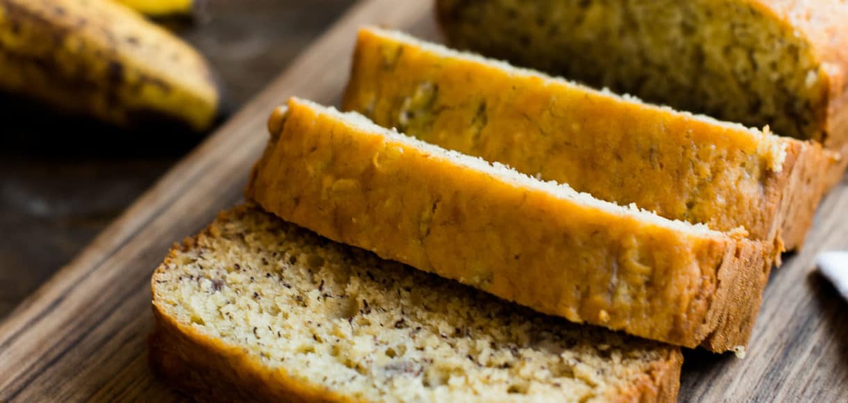 Banana bread sliced on a wooden cutting board.