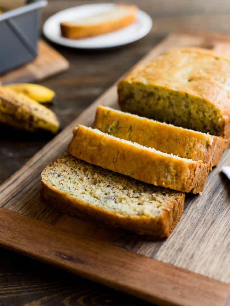 Banana bread sliced on a wooden cutting board.