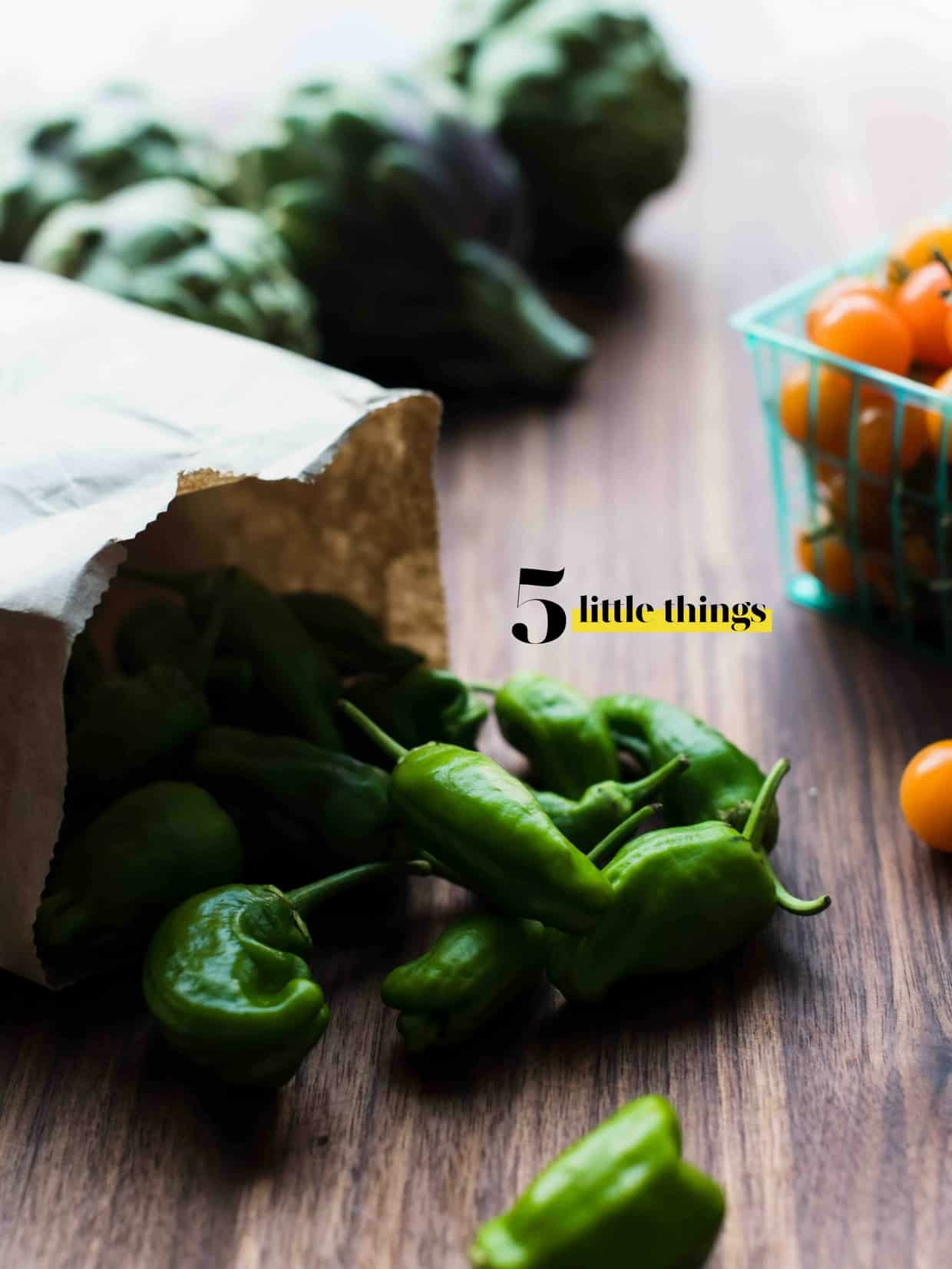 Peppers spilling from a paper bag on a wooden surface.