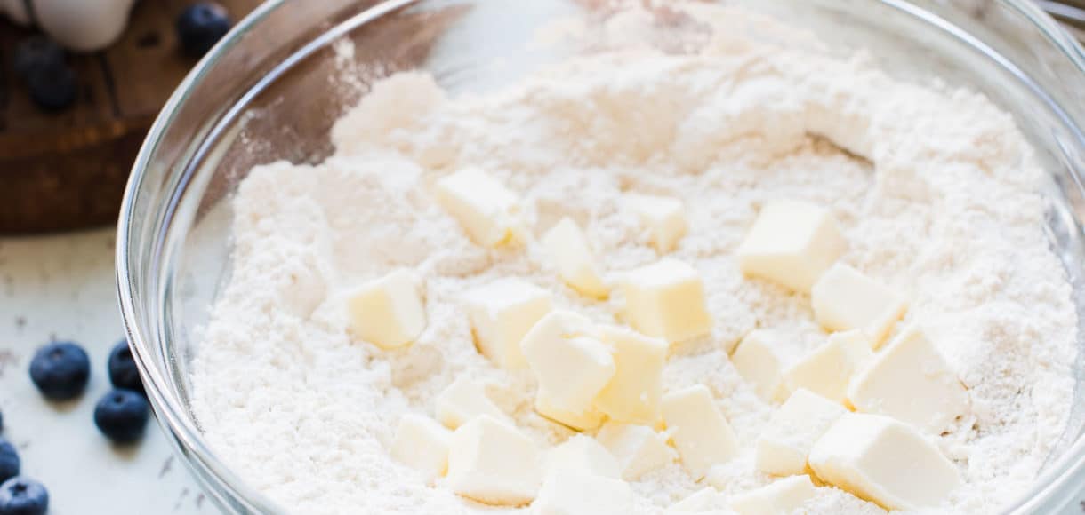 Ingredients for scones being creamed together in a glass bowl.