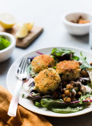 Chickpea crab cakes served on a salad with toasted chickpeas.