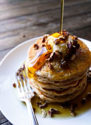 Stack of sweet potato pancakes with maple syrup pouring on top.