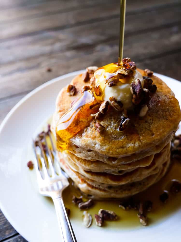 Stack of sweet potato pancakes with maple syrup pouring on top.