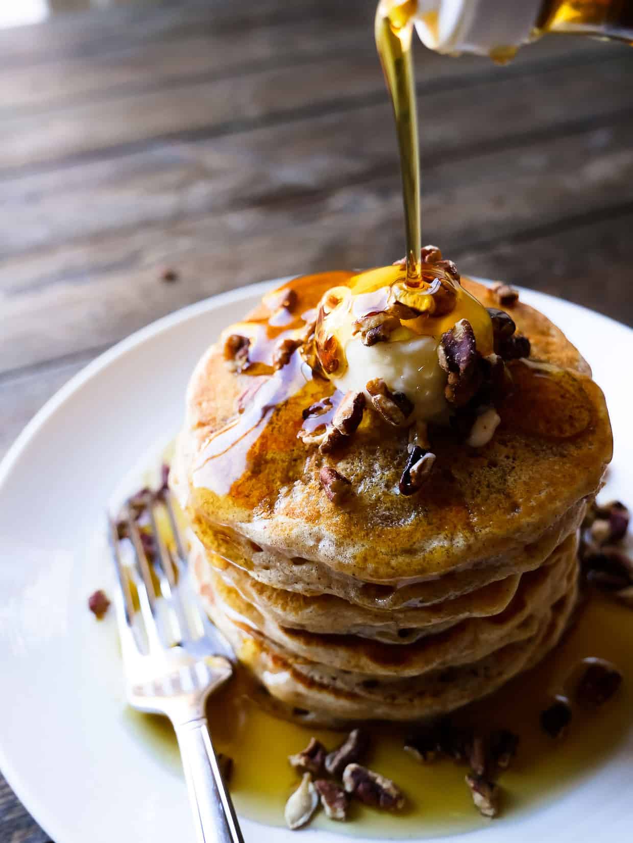 Stack of Sweet Potato Pancakes with syrup pouring down the sides.