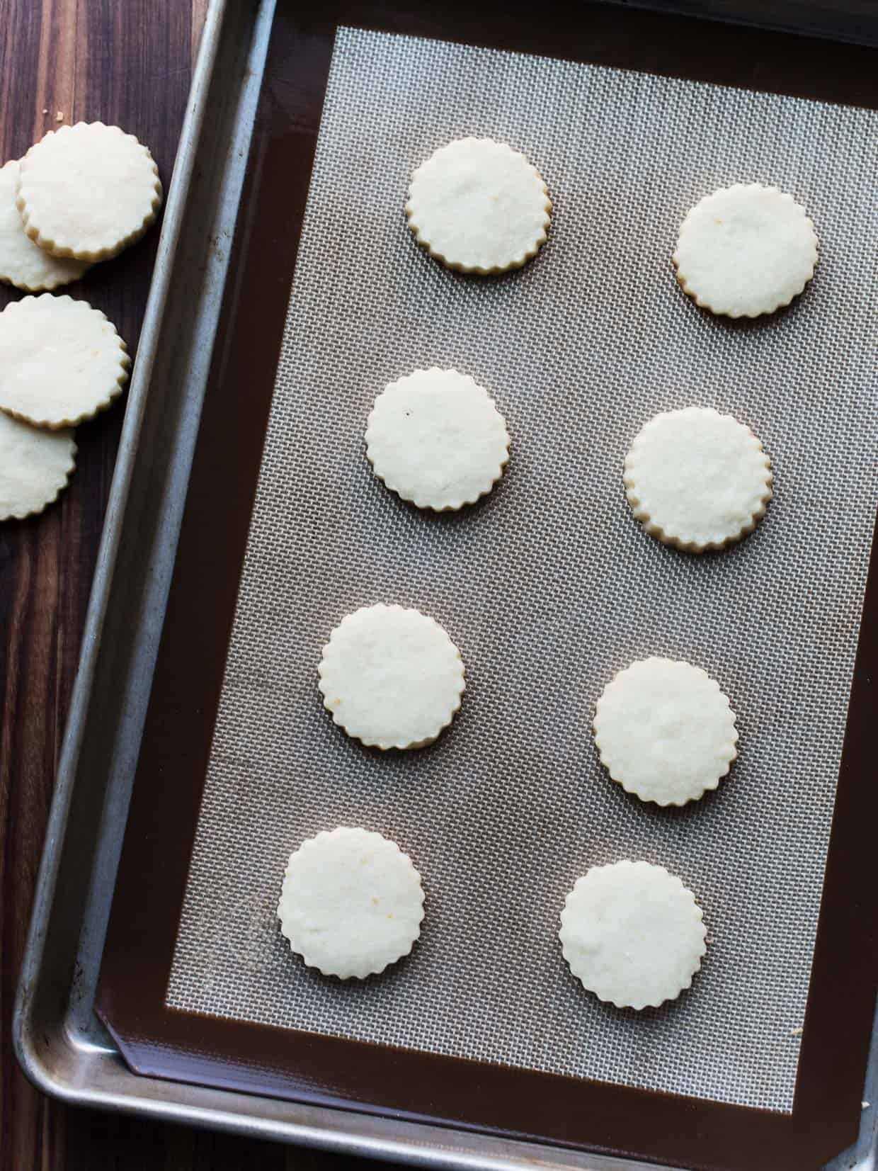 Alfajores (a sandwich cookie made with tender shortbread) on a baking sheet.