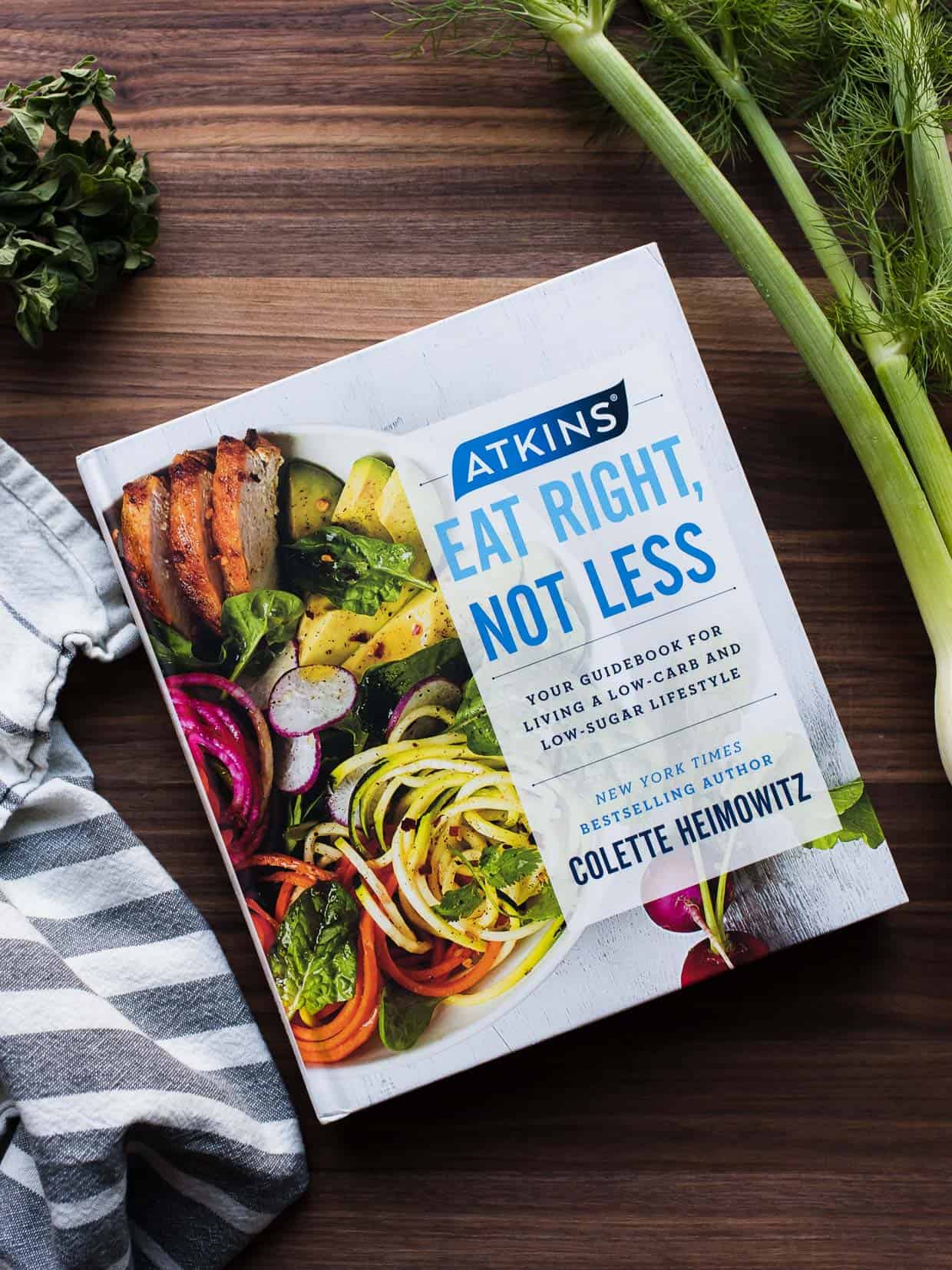 Atkins: Eat Right, Not Less guidebook surrounded by ingredients on a wooden board