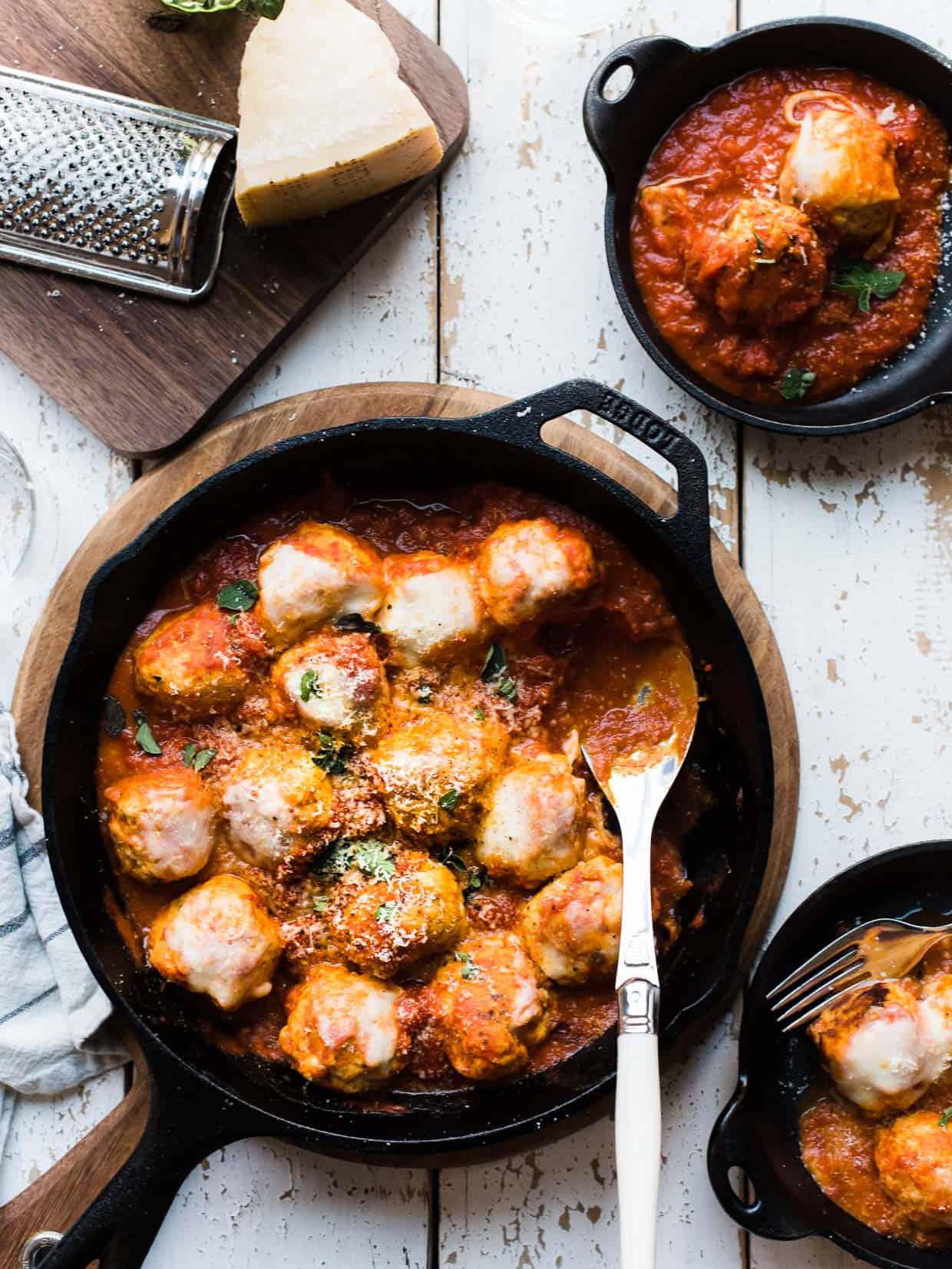 Chicken Parmesan Meatballs in a cast iron skillet on a white board background