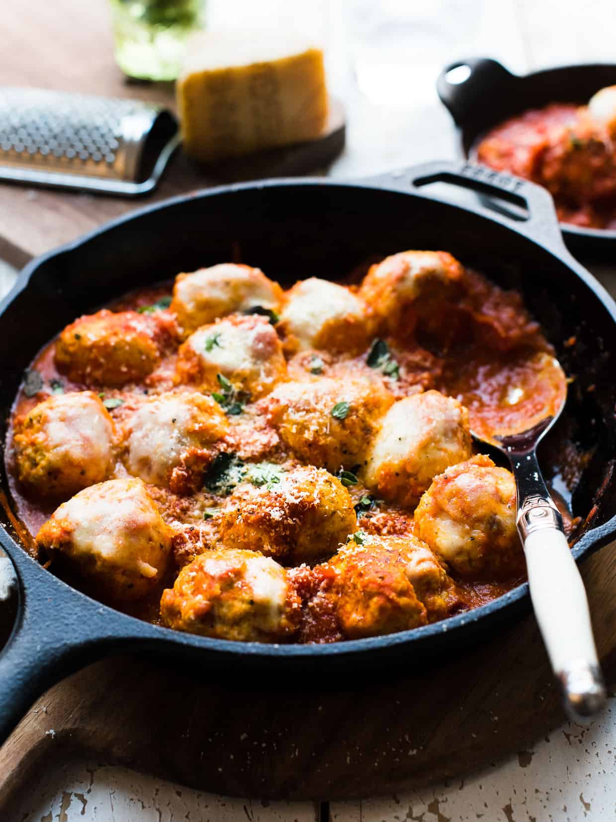 Chicken Parmesan Meatballs with melted cheese in a cast iron skillet